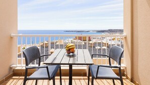 Un balcon avec une table et deux chaises, offrant une vue sur la côte.