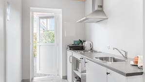 Cocina compacta con horno integrado, pileta de acero inoxidable y campana extractora.