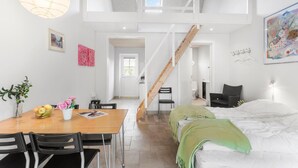 Un interior moderno con comedor, escalera, cama y baño.