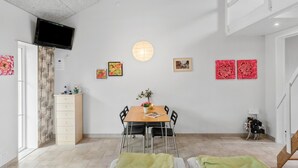 Una habitación moderna y bien iluminada con una mesa de comedor, sillas y un televisor montado en la pared.