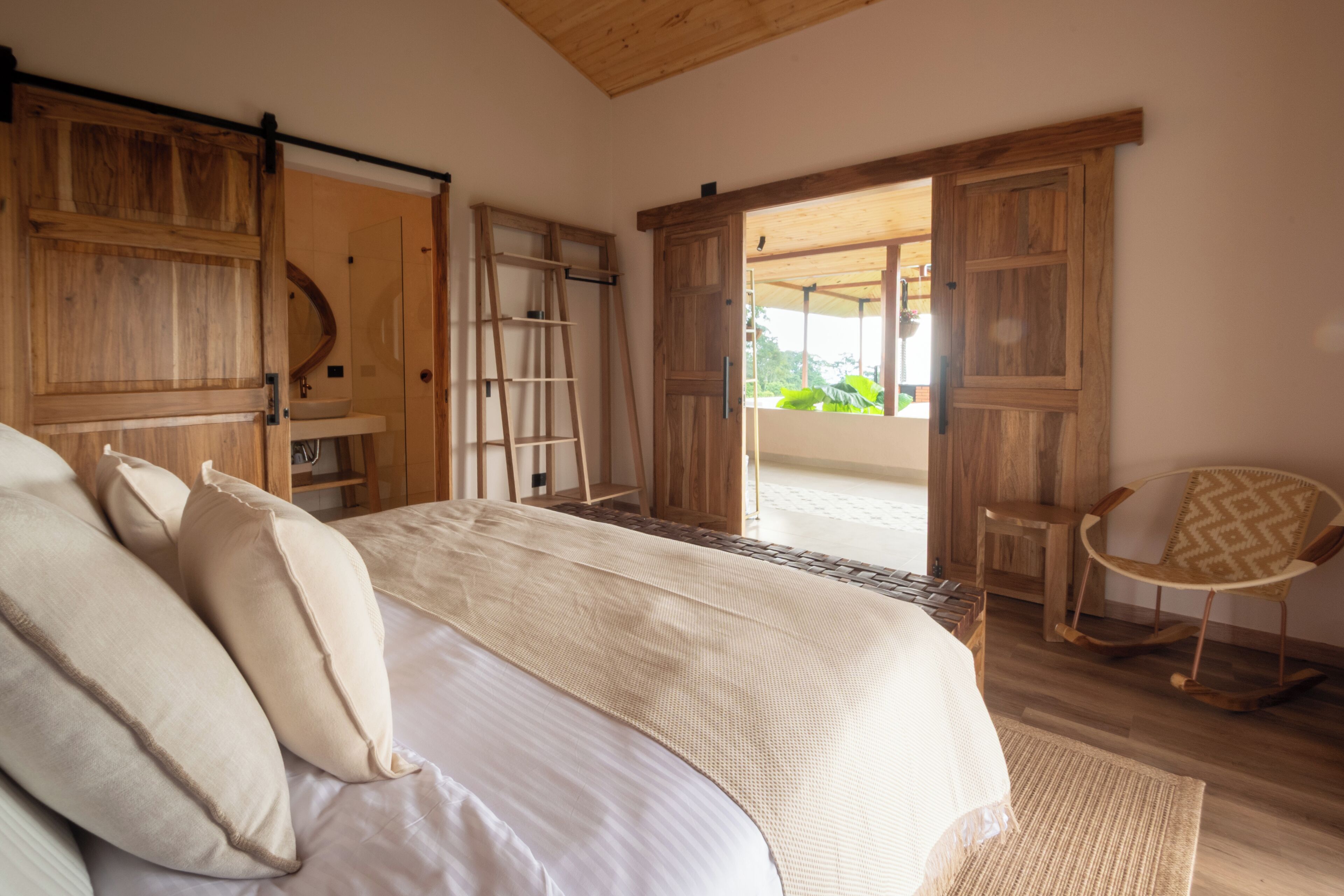 A bedroom with a large bed, wooden wardrobe, and a rocking chair.
