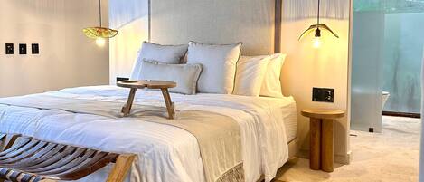 A modern bedroom with a wooden ceiling, a bed with white linens, a small round table, and a hanging light fixture.