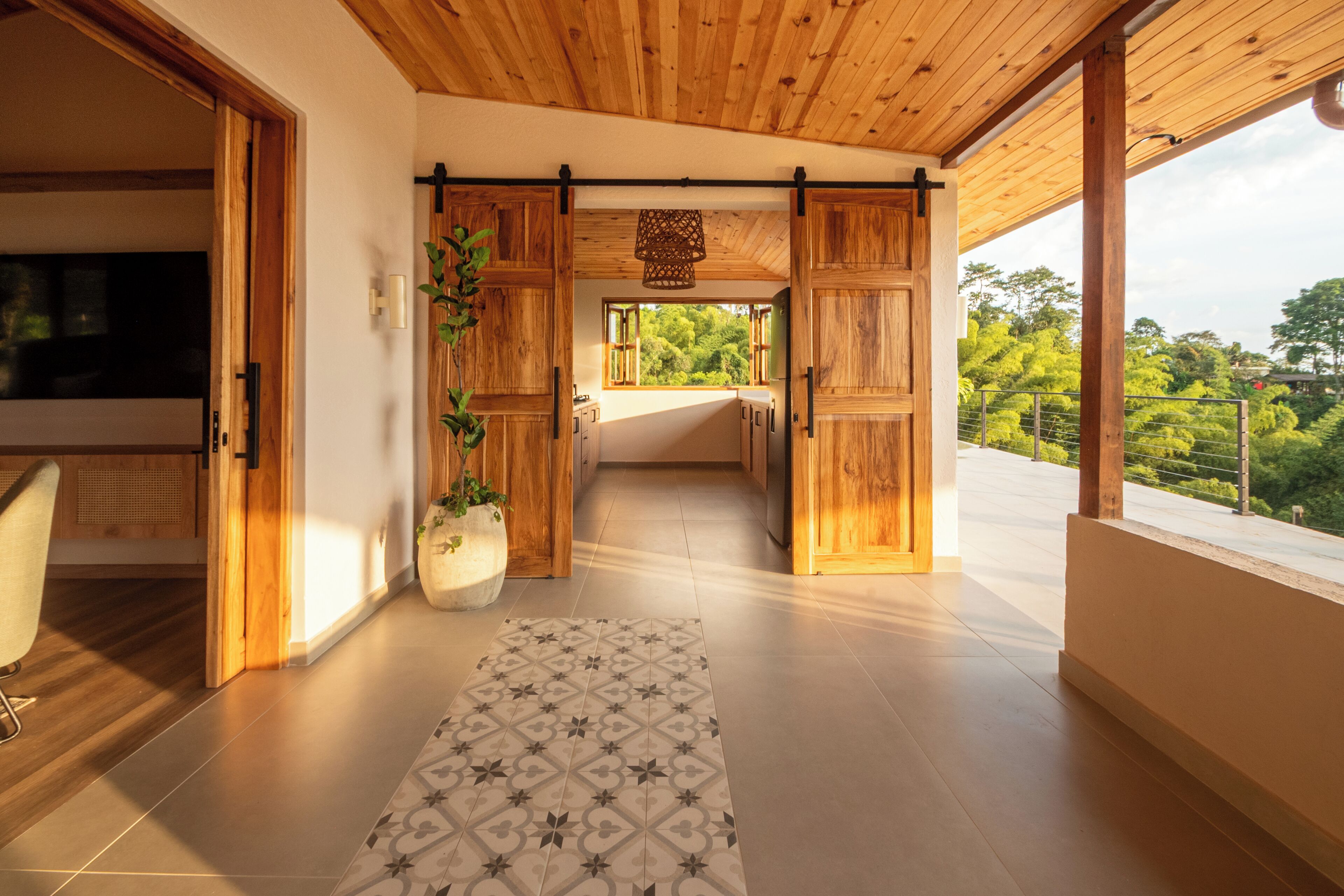 A modern interior with wooden flooring, a patterned rug, and a view of greenery outside.