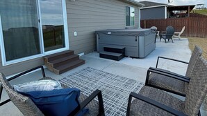 En baghave med terrasse, udendørs møbler og en overdækket siddeplads.