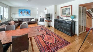 A modern living room with a sofa, dining table, and a patterned rug. - 3 bedroom cozy apartment in Gålå (Gålå)