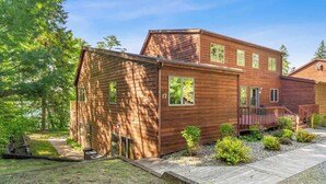 A two-story wooden cabin with a deck, surrounded by trees. - Lakeside Condo #17 3BR 3BA Timberlane Resort (Park Rapids)