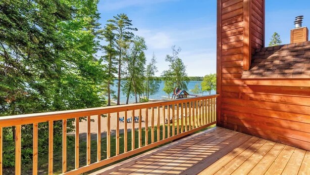 A wooden deck with a view of a lake and trees. - Lakeside Condo #17 3BR 3BA Timberlane Resort (Park Rapids)