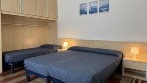 A bedroom with two beds, wooden cabinets, and wall art. - Villa Bianca 2 - Carraro Immobiliare Jesolo (Lido di Jesolo)
