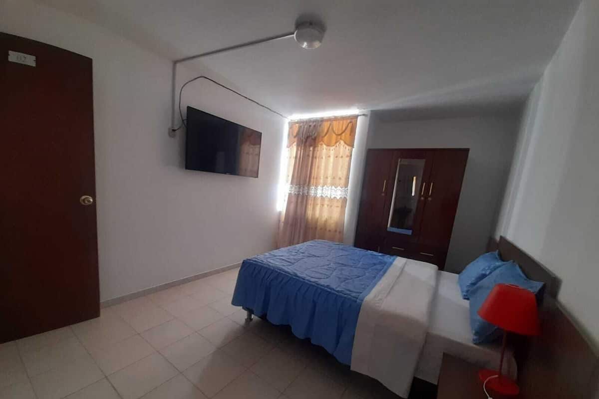 A bedroom with a bed, a TV, a wardrobe, and a red lamp.