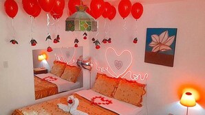 A hotel room with two beds, red balloons, a heart-shaped neon sign, and a flower painting. - Hotel Mi Secreto (Arequipa)