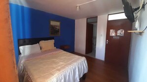 A bedroom with a bed, a nightstand, a wall-mounted air conditioner, and a door leading to another room. - Hotel Mi Secreto (Arequipa)
