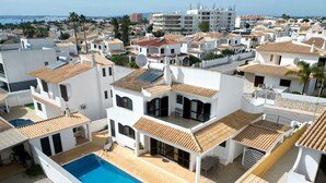 A residential area with white buildings, a swimming pool, and a view of the sea.