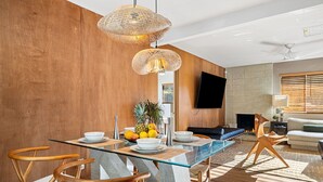 Un espace repas moderne avec une table en verre, des chaises en bois et un luminaire suspendu en fibres tressées.