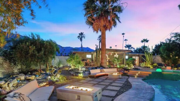Un espace aménagé au bord de la piscine, avec des sièges d’extérieur, un foyer et un jardin paysager.