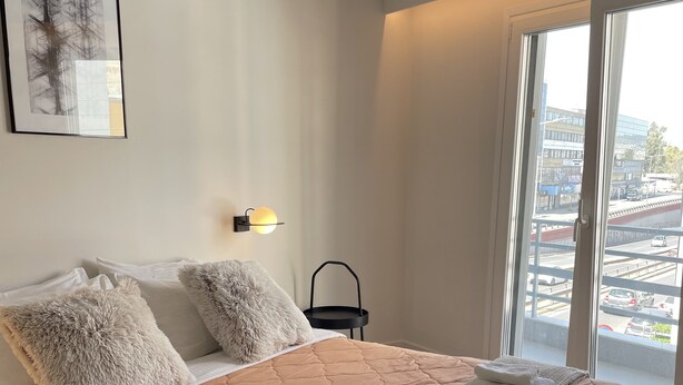 A neatly made bed with a brown quilt, fluffy pillows, and a white throw blanket. - Athens City Chic apartment  in Petralona,with 2 double bedrooms and 2 bathrooms (Athens)