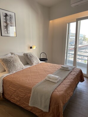 Ein ordentlich bezogenes Bett mit einer braunen Steudecke, weichen Kissen und einer weißen Tagesdecke.