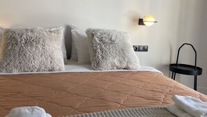 A neatly made bed with a textured blanket, two fluffy pillows, and a folded white towel. - Athens City Chic apartment  in Petralona,with 2 double bedrooms and 2 bathrooms (Athens)