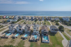 Un quartier résidentiel situé sur la côte, composé de plusieurs maisons à deux étages, d’une plage et d’une série de piscines.