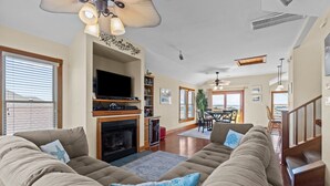 A spacious living room with a fireplace, a large sectional sofa, and a flat-screen TV. - 5711-OBX TA SEA - Semi-Oceanfront Escape w/ Pool & Hot Tub (Nags Head)