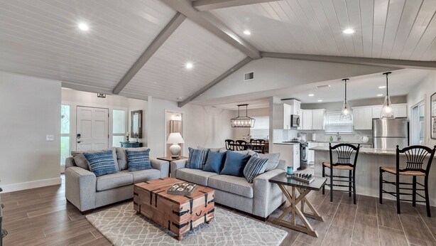 A spacious living area with a sectional sofa, a coffee table, and a kitchen in the background.