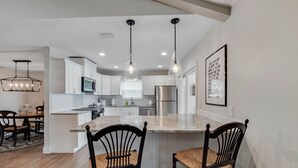 A modern kitchen with white cabinets, a central island, and pendant lighting.
