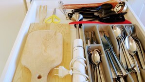 A kitchen drawer with utensils, a cutting board, and a plate with food.