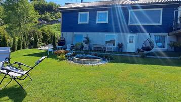 A two-story house with a well-maintained lawn and a small garden area.