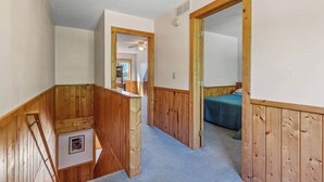 A hallway with wooden paneling, a staircase, and a bedroom with a bed. - Lakeside Condo #15 4BR 3BA Timberlane Resort (Park Rapids)