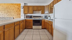 A kitchen with wooden cabinets, a stove, a microwave, and a refrigerator. - Lakeside Condo #15 4BR 3BA Timberlane Resort (Park Rapids)