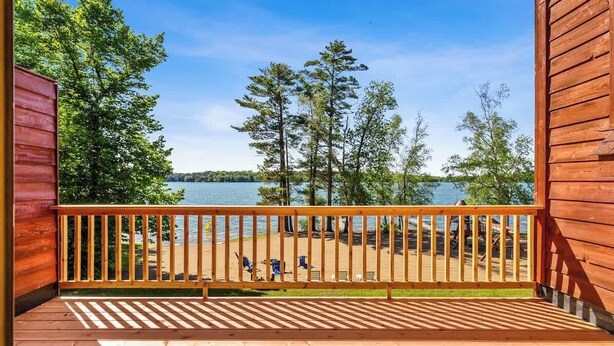 A wooden deck with a railing overlooking a lake and trees. - Lakeside Condo #15 4BR 3BA Timberlane Resort (Park Rapids)