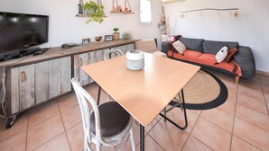 Un salon avec une table à manger en bois, un canapé et un téléviseur.