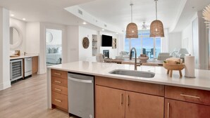 A modern kitchen with a central island, built-in dishwasher, and wooden cabinets.