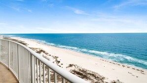 A beach with a white railing, clear blue sky, and calm sea.