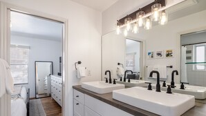 Une salle de bain moderne avec deux lavabos, un grand miroir et un meuble-lavabo en bois.