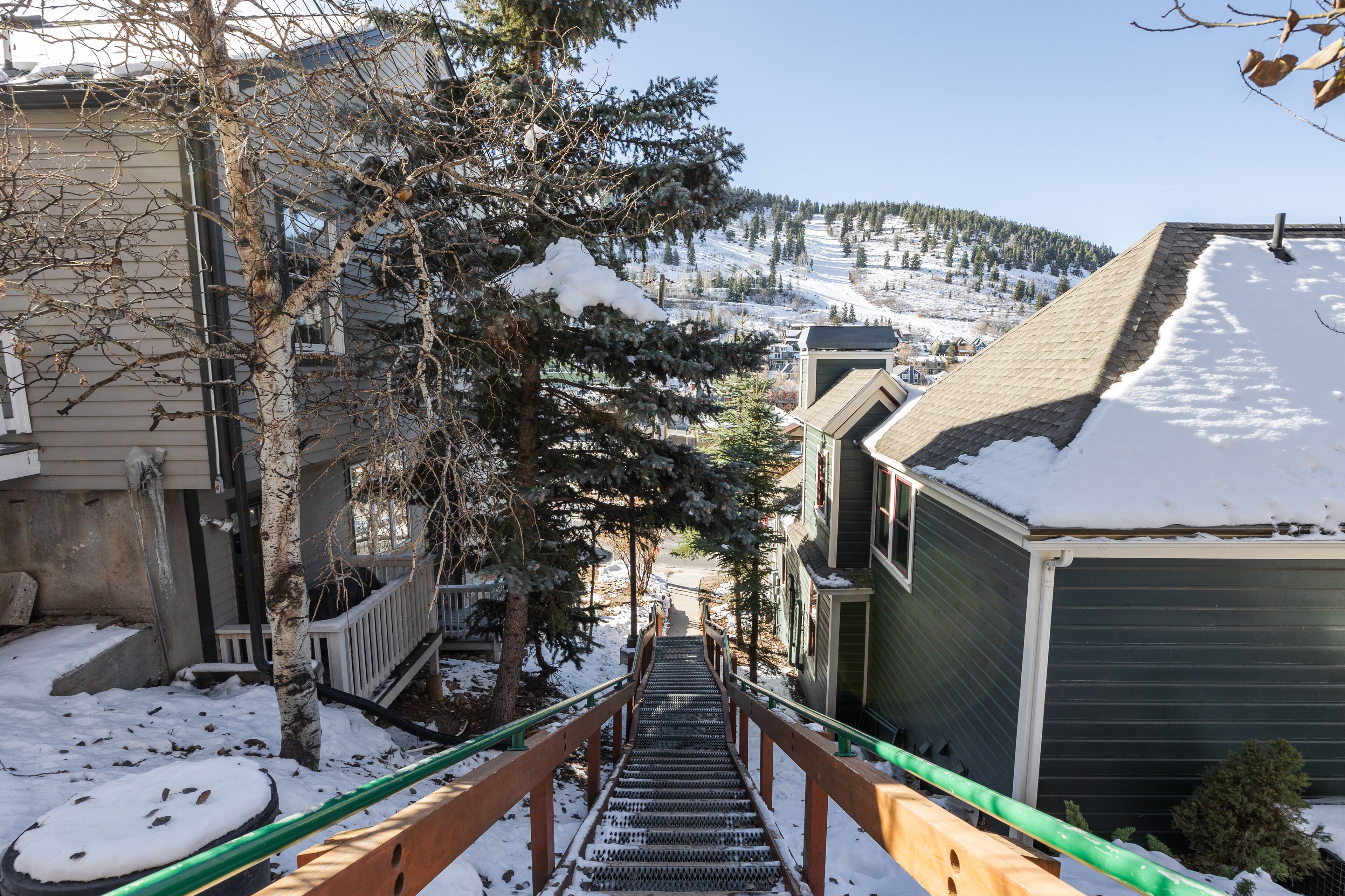 A snow-covered staircase leading to a building with a green exterior.