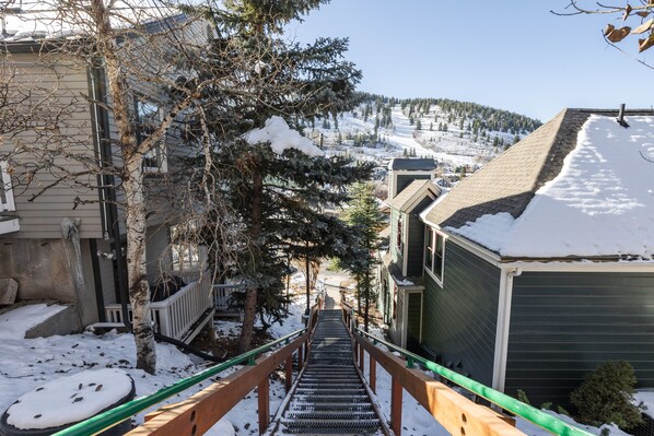 Eine mit Schnee bedeckte Treppe führt zu einem Gebäude mit grüner Fassade.