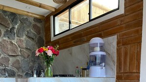 Eine Küche mit Steinwand, Holzstühlen, einem Tisch und einer Kaffeemaschine.