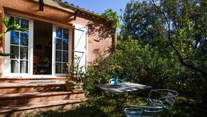 A patio with a table and chairs, a small garden, and a house with a window and door. - Lovely home in AFA with house a panoramic view (AFA)