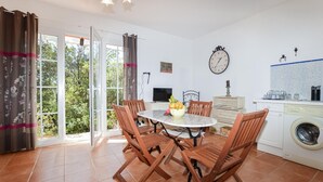 A dining area with a table and chairs, a washing machine, and a clock on the wall. - Lovely home in AFA with house a panoramic view (AFA)