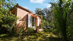 A small brick house with a white door and windows, surrounded by lush greenery and a clear sky. - Lovely home in AFA with house a panoramic view (AFA)