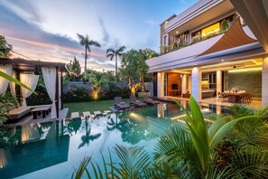 A modern house with a swimming pool, outdoor seating, and a well-maintained garden.