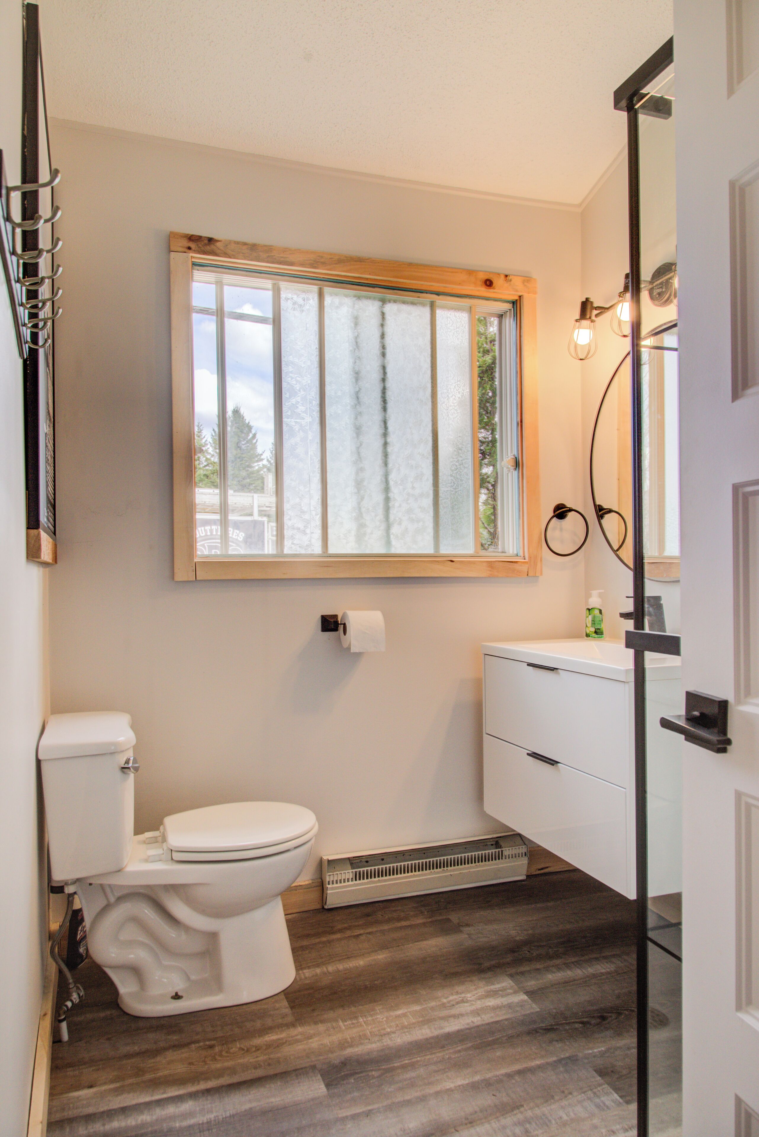 Une salle de bain équipée de toilettes, d’une fenêtre, d’un lavabo et d’un radiateur.