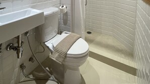 A modern bathroom with a white toilet, a sink, and a shower area.