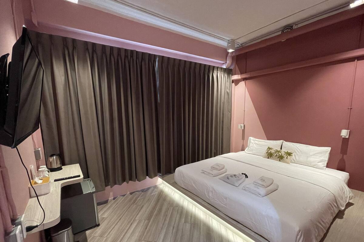 Een hotelkamer met een bed, een bureau, een stoel, een televisie en een raam met gordijnen.