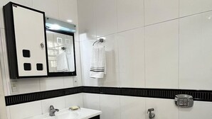 A modern bathroom with a white sink, black and white vanity, a black toilet, and a mirror above the sink.