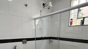 A modern bathroom with a glass shower enclosure, a black toilet, and a white tiled floor.