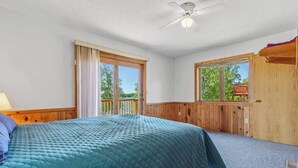 A bedroom with a bed, a ceiling fan, a window, and a wooden door. - Lakeside Condo #14 3BR 3BA Timberlane Resort (Park Rapids)