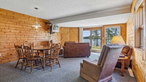 A cabin interior with a dining table, chairs, a sofa, and a fireplace. - Lakeside Condo #14 3BR 3BA Timberlane Resort (Park Rapids)