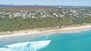 Vista aérea de una zona residencial costera con casas, una playa y una vista despejada del océano.