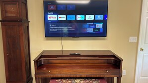 Un televisor de pantalla plana montado en la pared sobre un mueble de entretenimiento de madera con un banco tapizado en rojo.